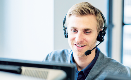 Man in customer service wearing headset and answering a call looking at a computer screen