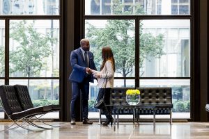 Two people dressed formally shaking hands in the lobby of a building