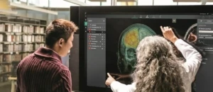 A patient and a doctor examining a neuro scan on a large computer monitor