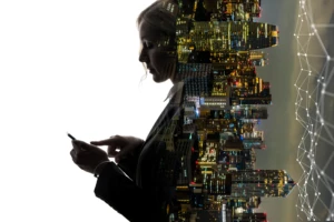 woman looking at her cellphone in left half of the image, city skyline on right half