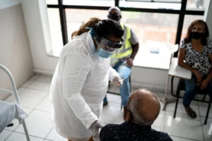 Mature doctor talking to senior man before applying vaccine - wearing face mask