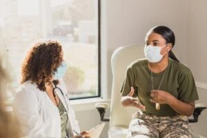 A doctor and a patient speaking to one another with face masks on.