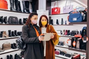 Two females in retail store looking at a handbag with masks on