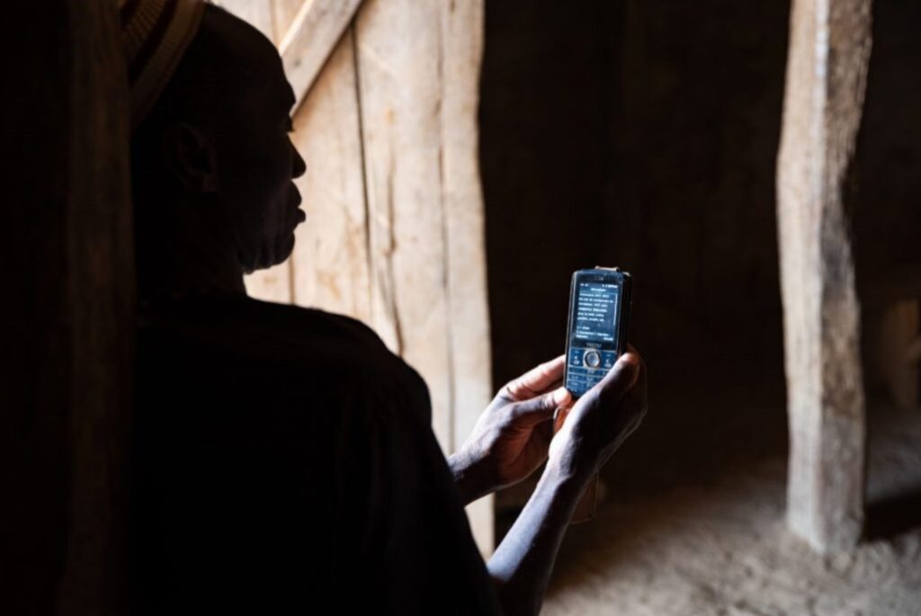 携帯電話で保険の支払いをするマリ共和国トゥレラ市の住民