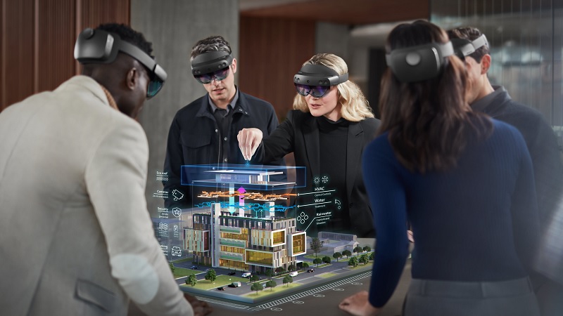 Mehrere Mitarbeiter tragen HoloLenses und arbeiten zusammen an einem virtuellen Gebäudemodell