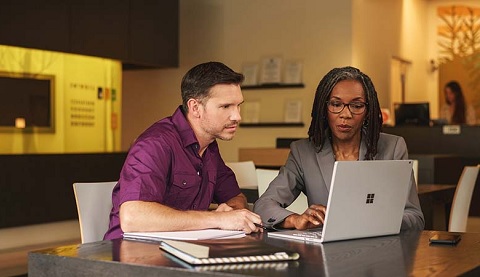 Ein Mann und eine Frau sitzen am Tisch und schauen gemeinsam auf einen Laptop