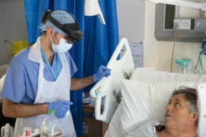 An NHS doctor at St. Mary’s Hospital speaks with a patient on a COVID-19 ward during the pandemic whilst wearing a Microsoft HoloLens 2