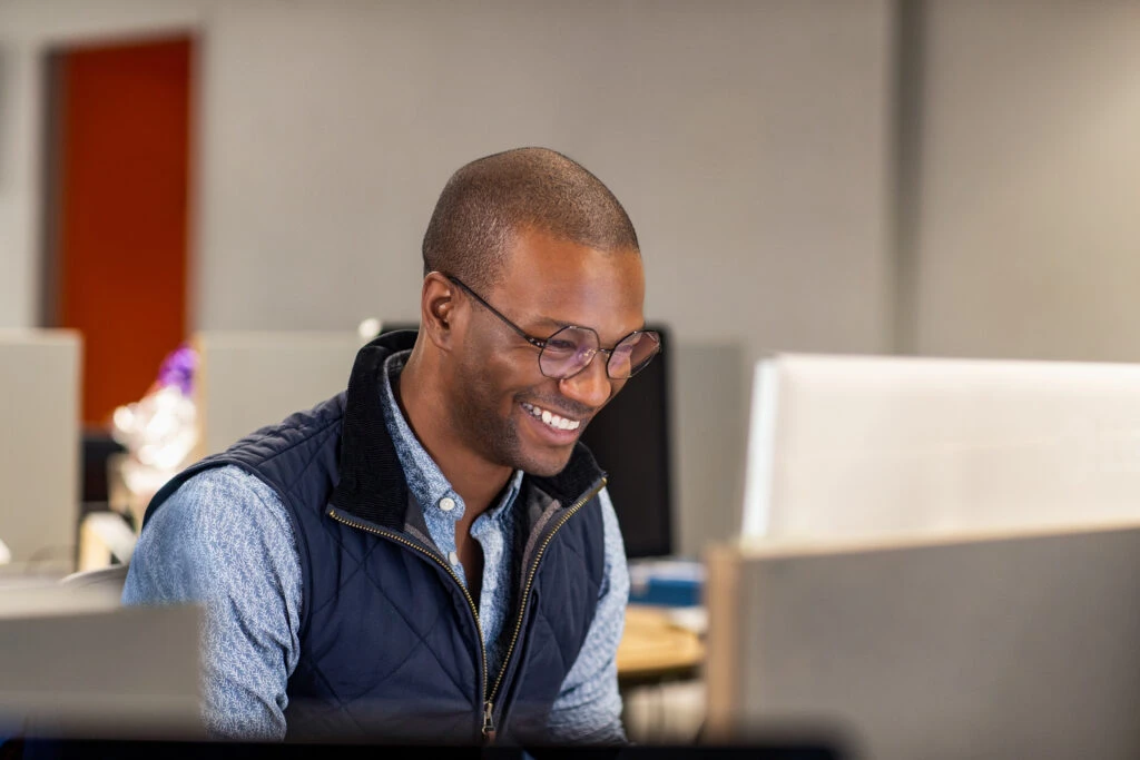 Black male developer smiling while at work in an Enterprise office workspace.