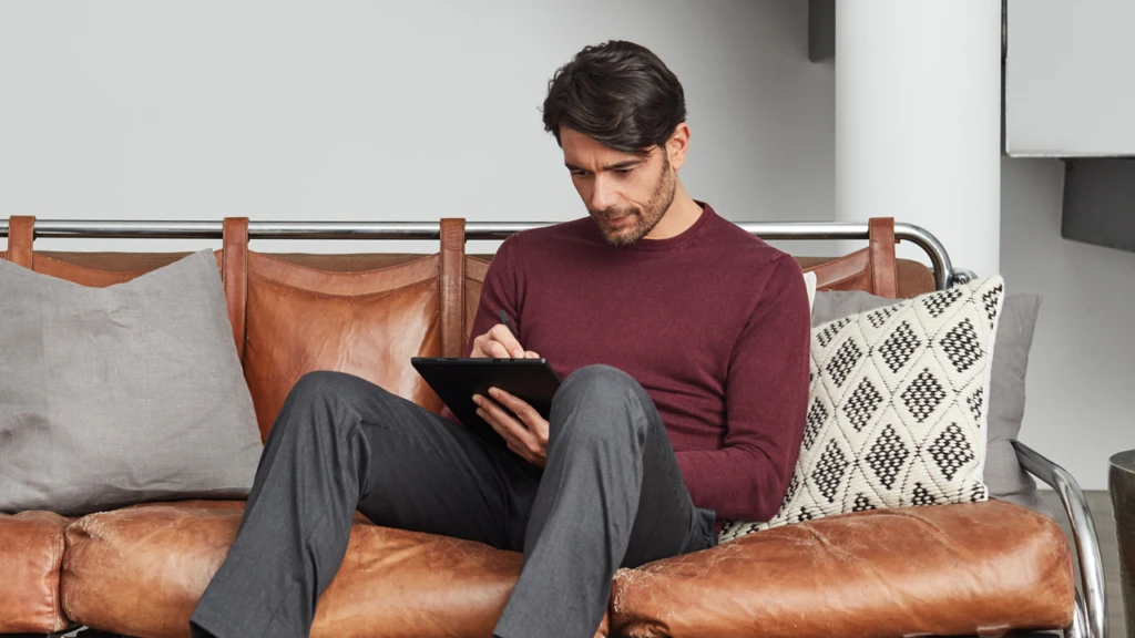 man sitting on the couch looking down at his tablet