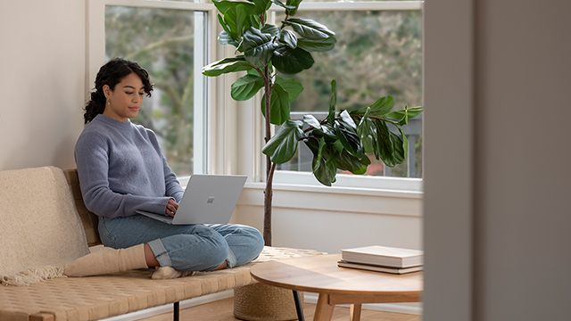Woman sitting on the couch working on her Surface laptop