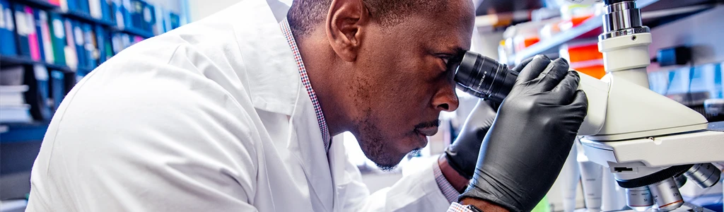 Homem olhando no microscópio.