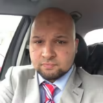 a man wearing a suit and tie sitting in a car