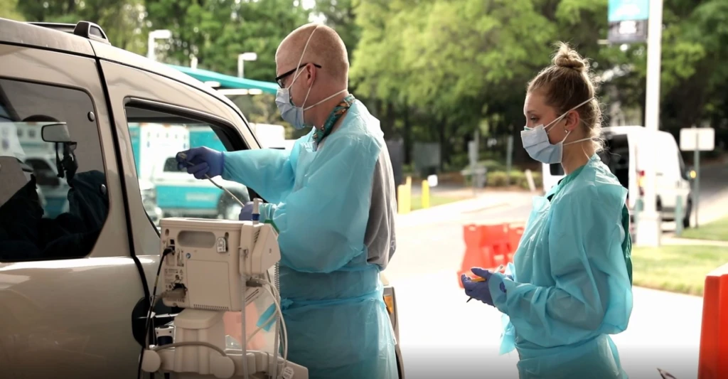 a man and a woman standing in front of a car