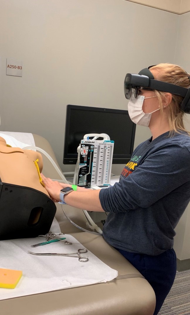 A nursing student practicing a catheterization procedure on a mannequin with HoloLens 2. 